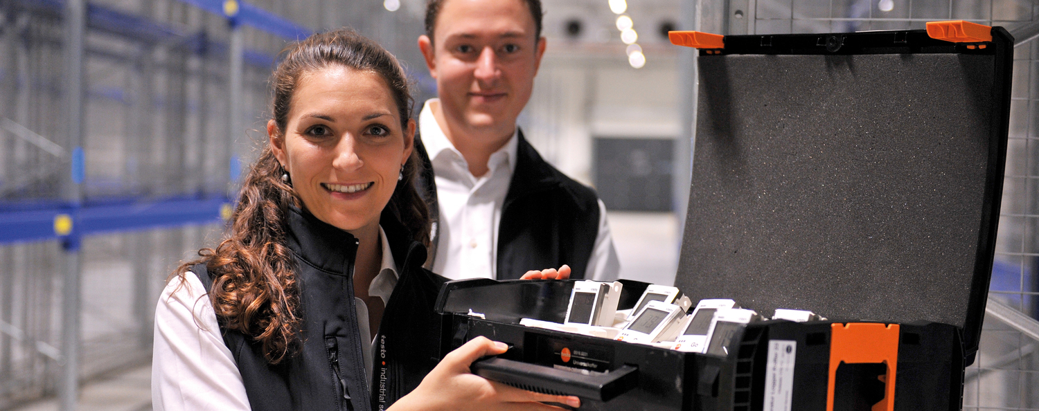 Professionelle Klimaverteilungsmessung Mitarbeiter von Testo Industrial Services stehen mit einem Koffer voller Datenlogger in einem Hochregallager und bereiten ein Mapping vor.